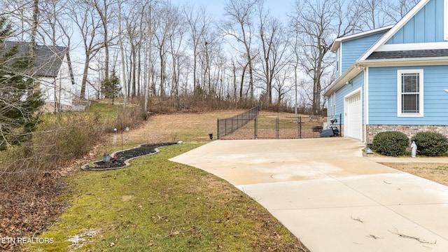 view of yard with a garage, driveway, and fence