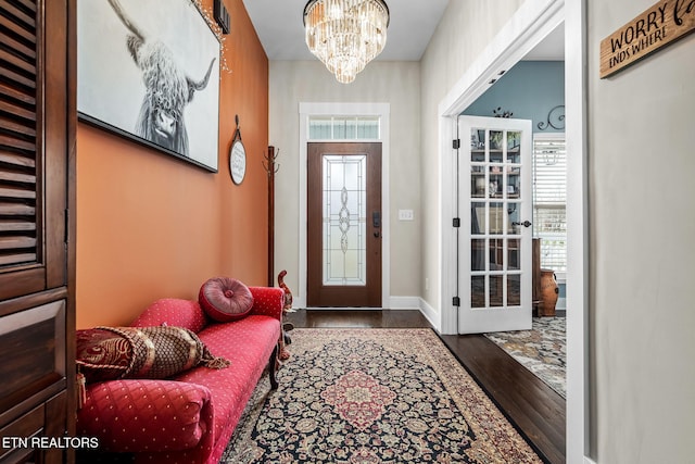 entrance foyer featuring a healthy amount of sunlight, a notable chandelier, baseboards, and wood finished floors