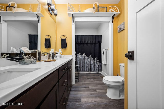 full bath featuring double vanity, a sink, toilet, and wood finished floors