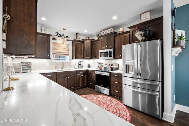 kitchen with dark wood-type flooring, a sink, dark brown cabinets, appliances with stainless steel finishes, and tasteful backsplash