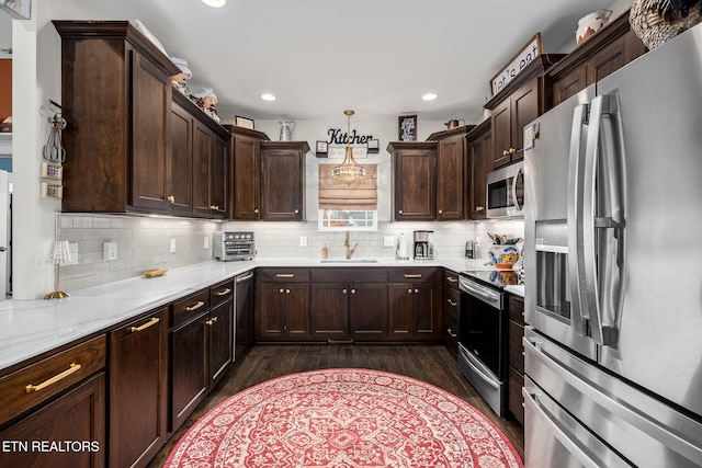 kitchen with appliances with stainless steel finishes, dark brown cabinetry, decorative backsplash, and a sink