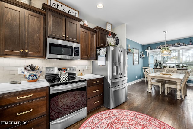 kitchen featuring appliances with stainless steel finishes, dark wood-style flooring, light countertops, dark brown cabinets, and backsplash