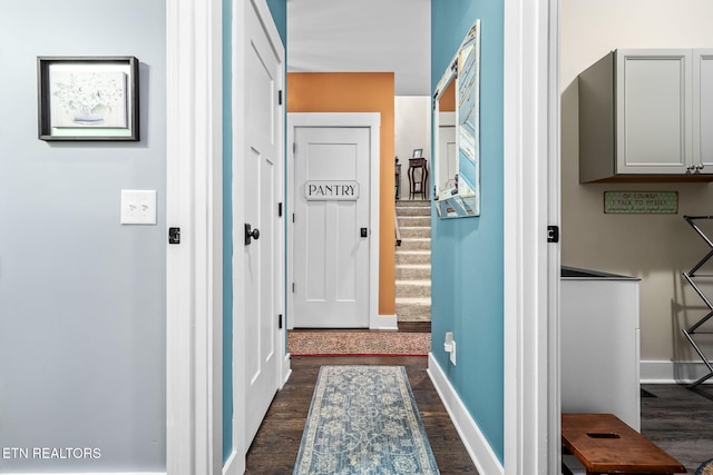 hallway with stairway, dark wood-style flooring, and baseboards