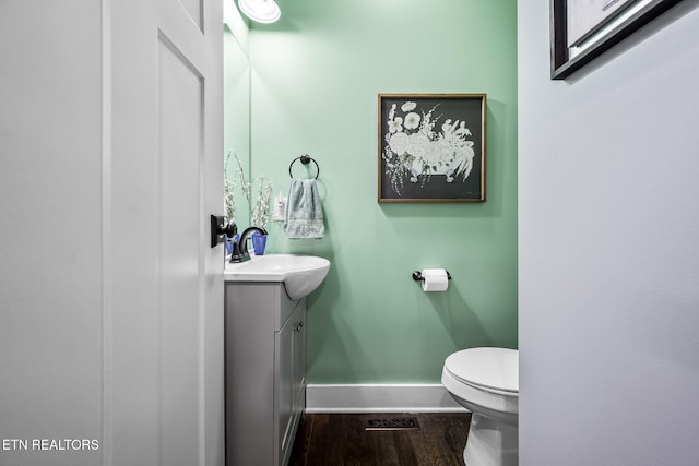 bathroom with visible vents, baseboards, toilet, wood finished floors, and vanity