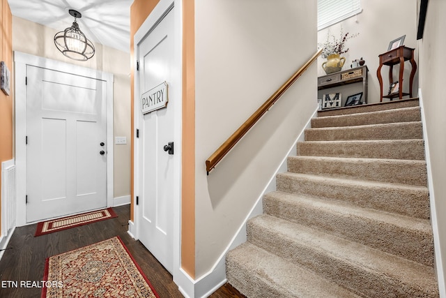 foyer entrance featuring dark wood-type flooring, baseboards, and stairs