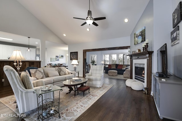 living room with a ceiling fan, dark wood-type flooring, a lit fireplace, high vaulted ceiling, and recessed lighting