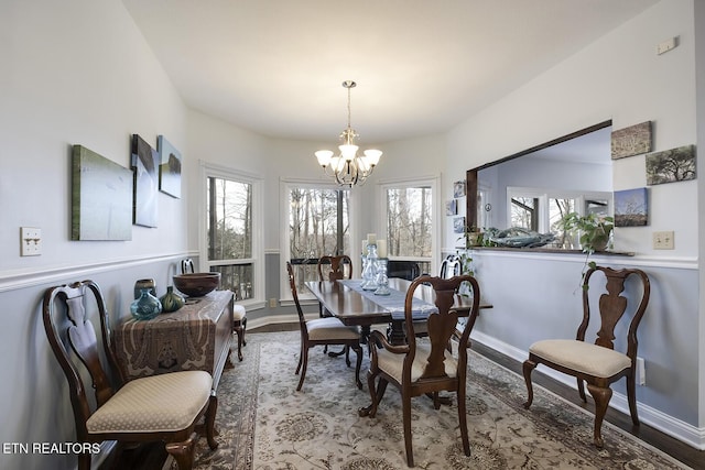 dining space featuring wood finished floors, plenty of natural light, baseboards, and an inviting chandelier