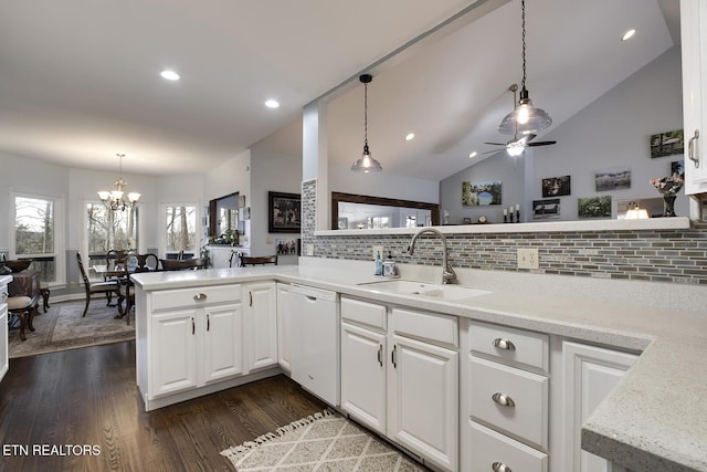 kitchen featuring dark wood-style flooring, light countertops, vaulted ceiling, white dishwasher, and a sink