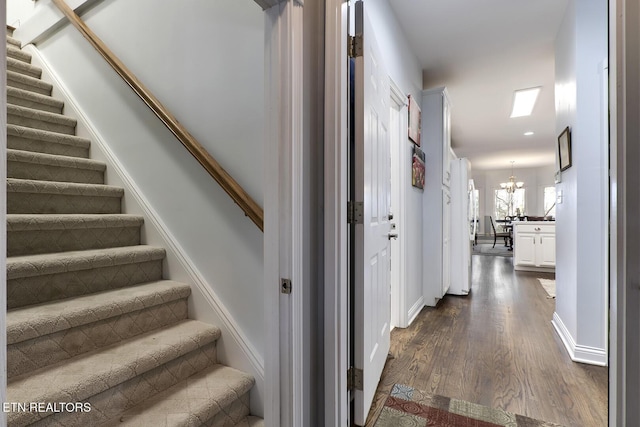 stairway with a chandelier, baseboards, and wood finished floors