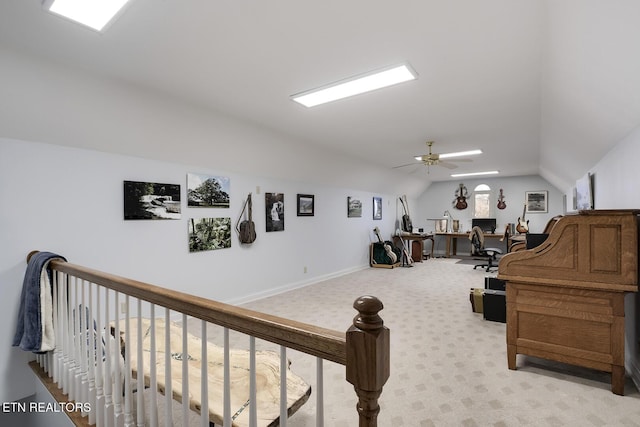 office area with vaulted ceiling, ceiling fan, baseboards, and light colored carpet