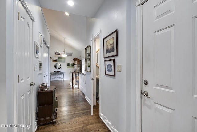 hall with vaulted ceiling, dark wood-style floors, and baseboards