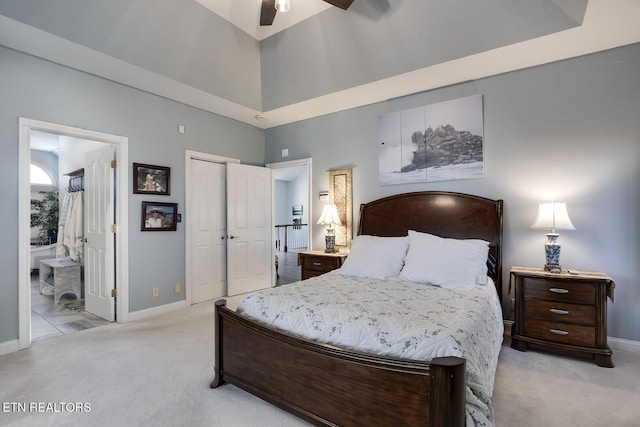 bedroom featuring a towering ceiling, baseboards, connected bathroom, and light colored carpet