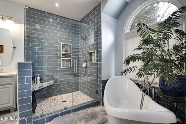 bathroom with a soaking tub, a tile shower, and vanity