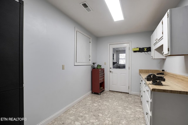 kitchen featuring butcher block counters, visible vents, baseboards, and white cabinetry