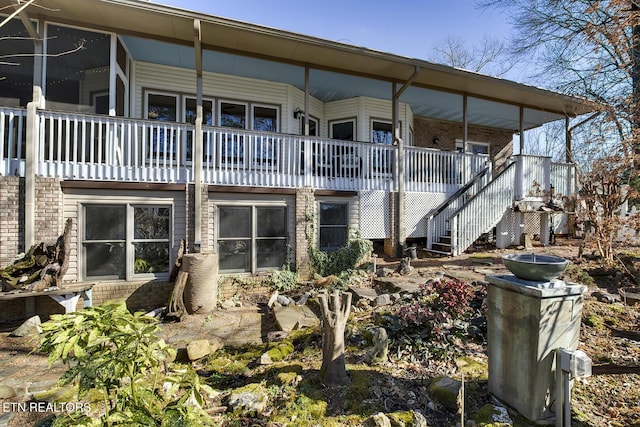 back of house with covered porch, stairway, and brick siding