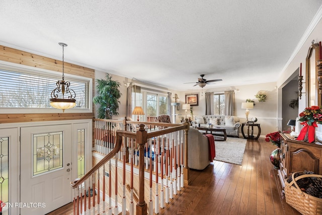 interior space with a textured ceiling, dark wood-style flooring, and an upstairs landing