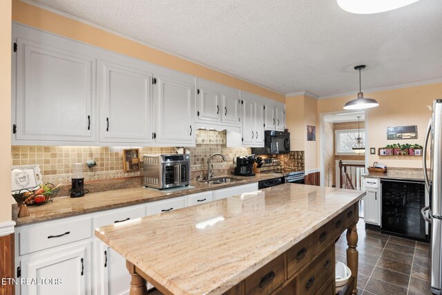 kitchen featuring stainless steel appliances, backsplash, white cabinets, a sink, and light stone countertops