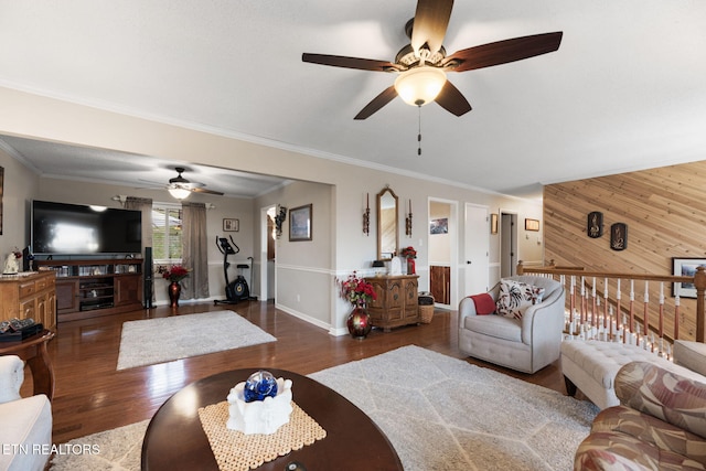 living area with ornamental molding, wooden walls, and wood finished floors