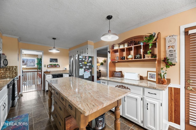 kitchen with freestanding refrigerator, a center island, white cabinetry, and crown molding