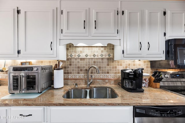 kitchen with light stone counters, a toaster, appliances with stainless steel finishes, white cabinetry, and a sink