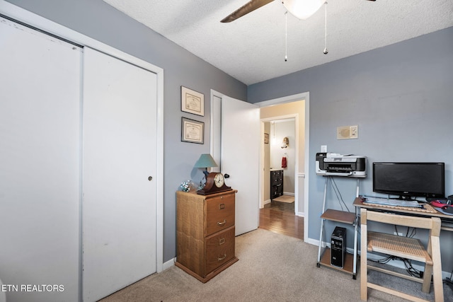 home office featuring carpet, ceiling fan, a textured ceiling, and baseboards