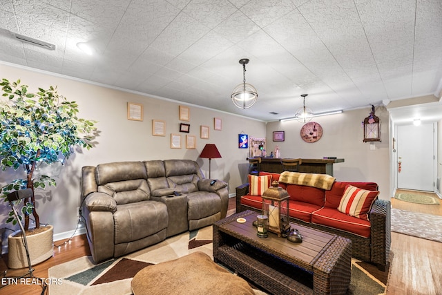 living area featuring ornamental molding, wood finished floors, visible vents, and baseboards