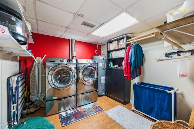 clothes washing area with laundry area, wood finished floors, washing machine and clothes dryer, and electric water heater