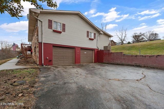 view of property exterior with driveway, a garage, and a yard