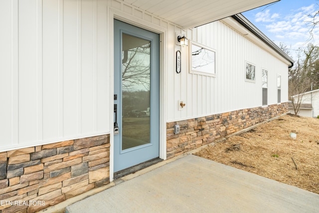 property entrance with stone siding and board and batten siding