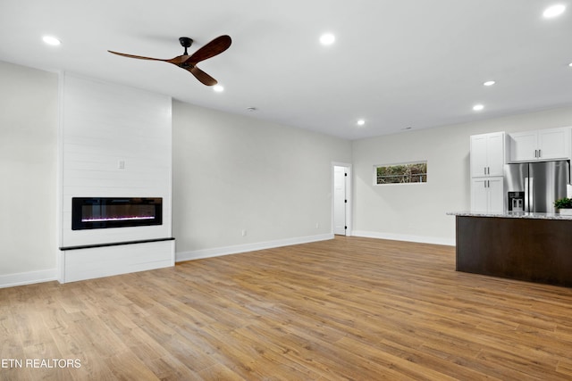 unfurnished living room featuring a large fireplace, baseboards, ceiling fan, light wood-style floors, and recessed lighting