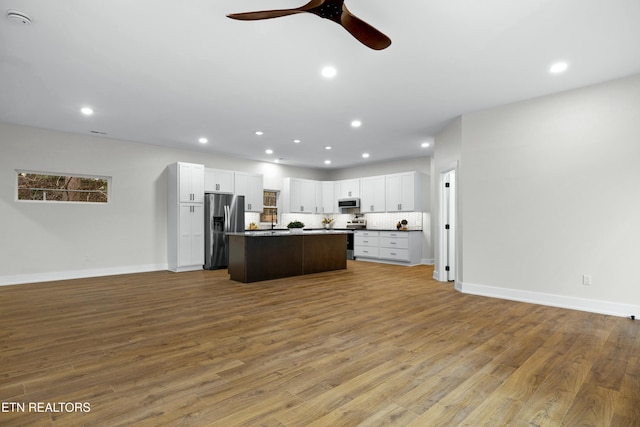 kitchen featuring backsplash, appliances with stainless steel finishes, open floor plan, and wood finished floors