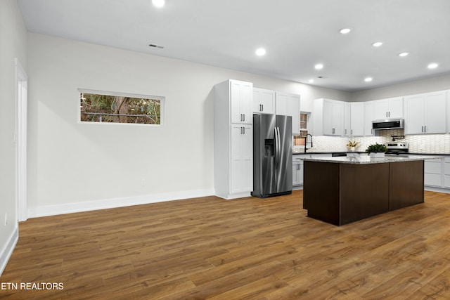 kitchen featuring a kitchen island, appliances with stainless steel finishes, dark wood-style flooring, backsplash, and recessed lighting