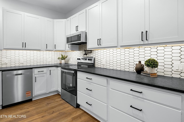 kitchen with stainless steel appliances, backsplash, dark countertops, and wood finished floors