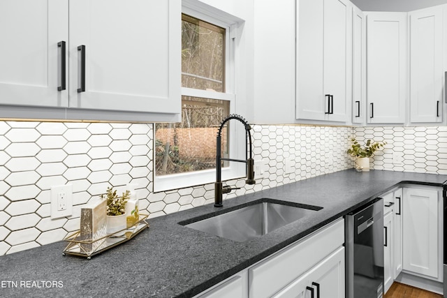 kitchen featuring stainless steel dishwasher, white cabinets, and a sink