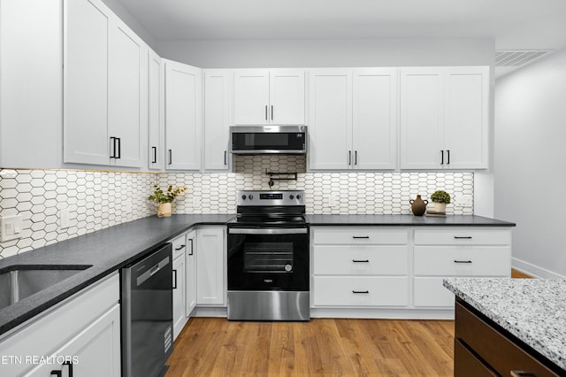 kitchen featuring visible vents, white cabinets, appliances with stainless steel finishes, backsplash, and light wood finished floors