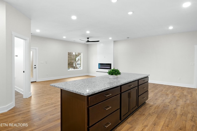 kitchen featuring a large fireplace, light wood-style flooring, a ceiling fan, and recessed lighting