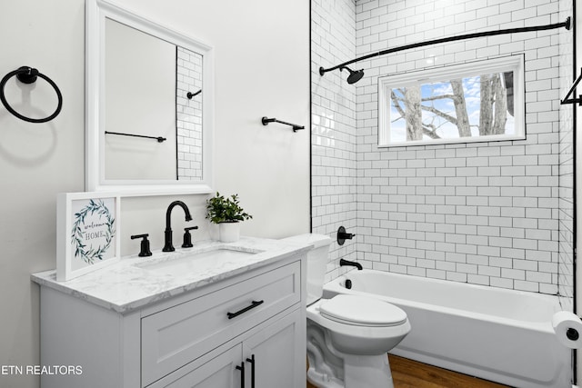 bathroom featuring toilet, shower / bathing tub combination, wood finished floors, and vanity