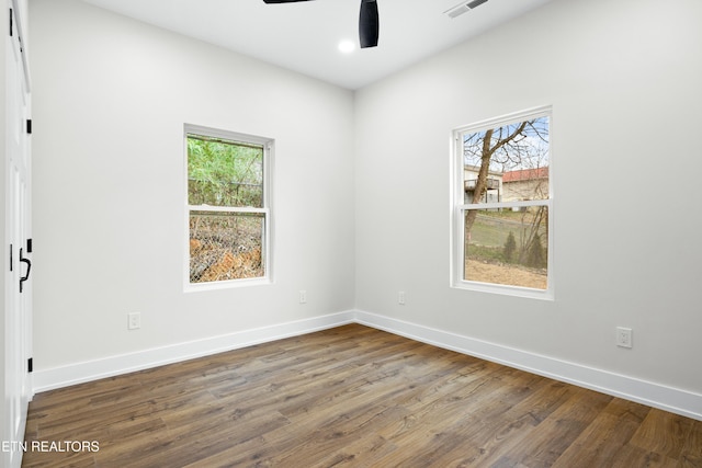 empty room with a ceiling fan, visible vents, baseboards, and wood finished floors