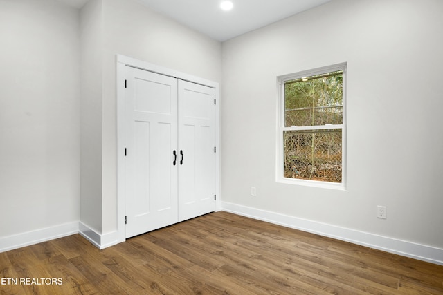 unfurnished bedroom with a closet, baseboards, and wood finished floors