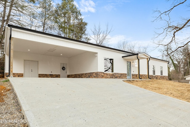 view of front of property with concrete driveway, a carport, and stone siding