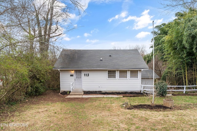 back of property featuring entry steps, fence, and a lawn