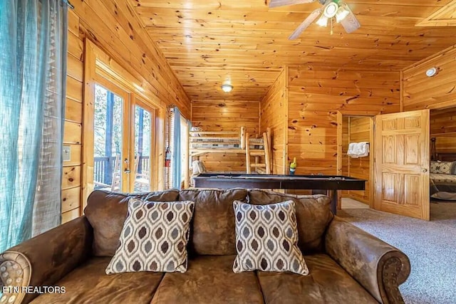 carpeted living room with wood ceiling, wood walls, and ceiling fan