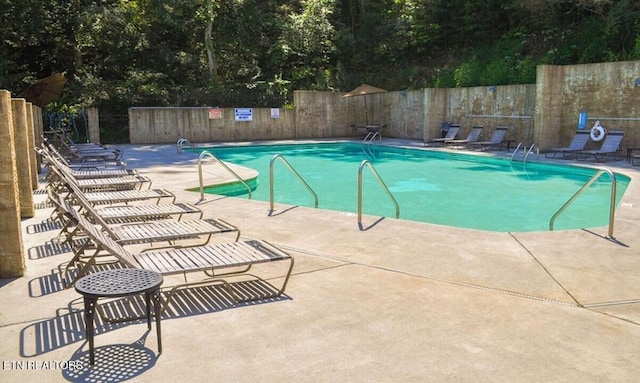 pool with a patio area and fence