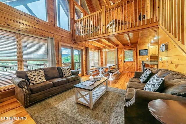 living room with high vaulted ceiling, light wood-style flooring, and wooden walls