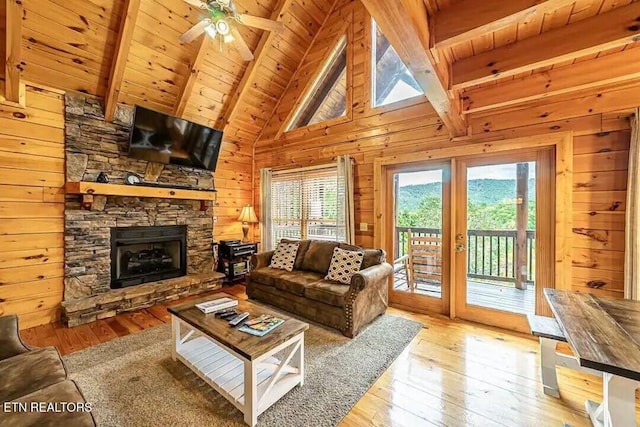 living area with a stone fireplace, wood walls, wood ceiling, beam ceiling, and wood-type flooring