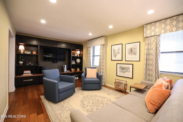 living area with baseboards, wood finished floors, and recessed lighting