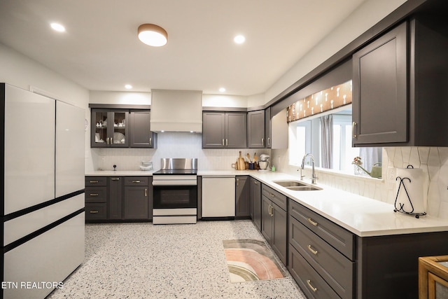 kitchen with a sink, stainless steel range with electric cooktop, light countertops, custom exhaust hood, and backsplash