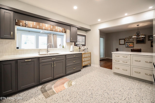 kitchen featuring tasteful backsplash, recessed lighting, light countertops, a sink, and baseboards