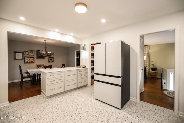 kitchen featuring recessed lighting, white cabinetry, a chandelier, a peninsula, and baseboards