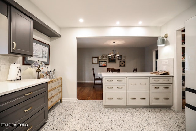 kitchen with a chandelier, recessed lighting, a peninsula, light countertops, and decorative backsplash